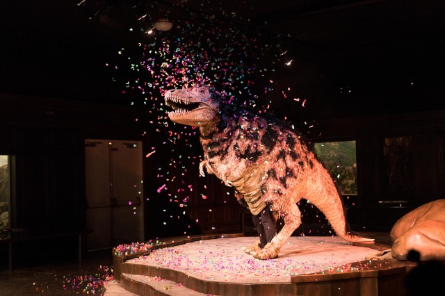 Person in dinosaur costume with colorful confetti falling