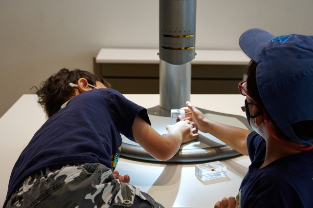 Children holding a specimen under a microscope