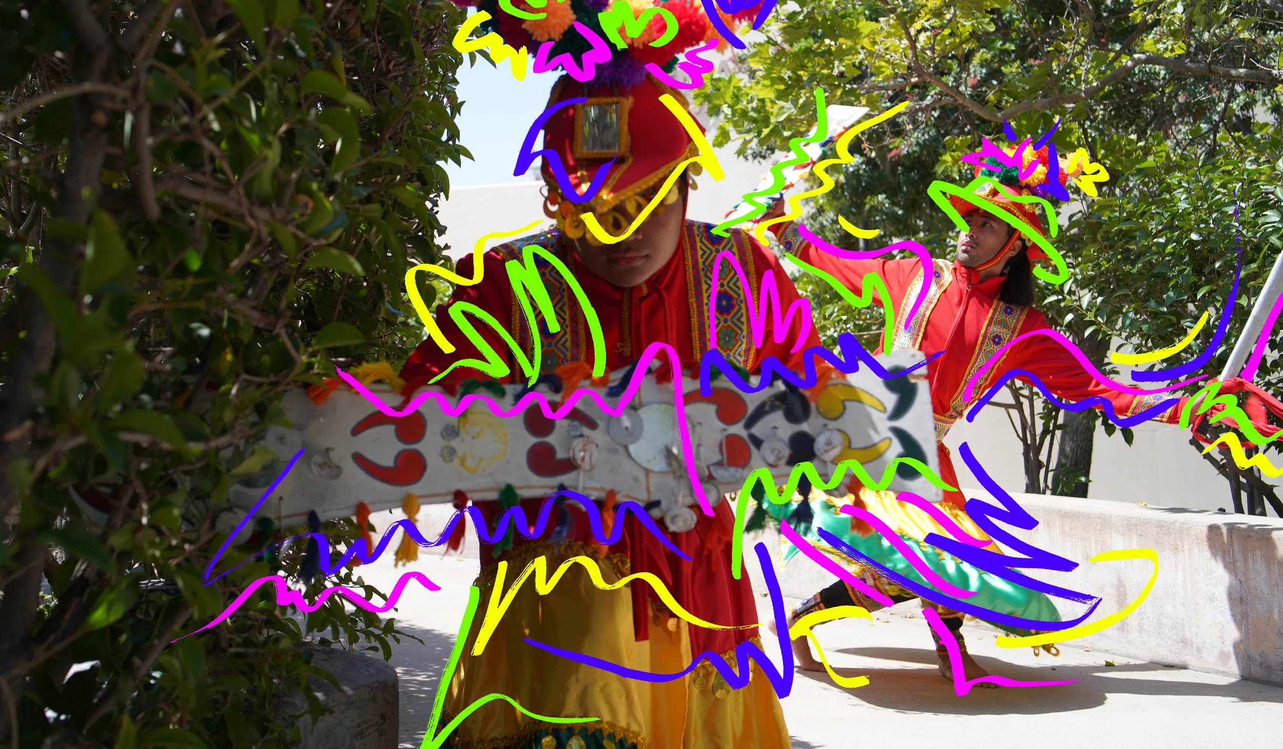 Two dancers wearing red headpieces and clothing with yellow, green, and purple squiggly shapes over them