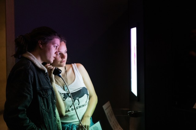 Visitors listen to recorded audio about exhibition object using a telephone