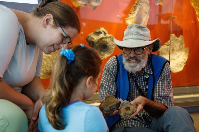 Volunteer with visitors holding fossils