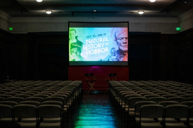 Image of the North American Mammal Hall with a film screen and seats 