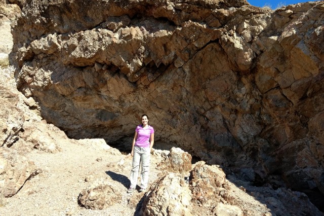 Juliet Hook standing in the sun outside the mountainous entrance to Gypsum Cave.