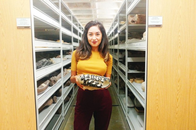 Michelle Barboza holding a fossil specimen in a collection room. 