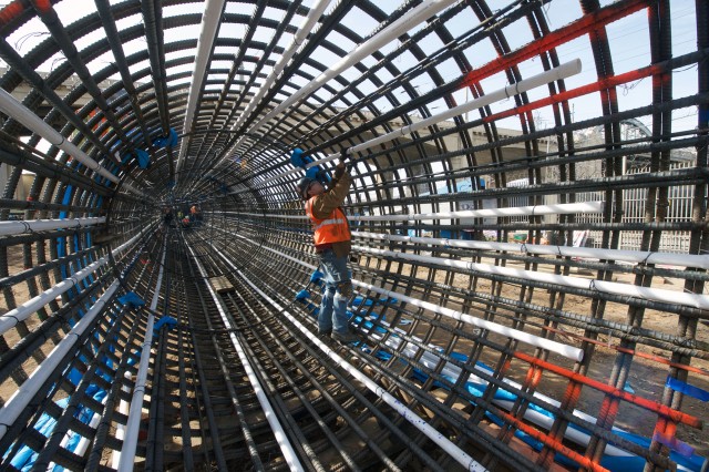 Photo of workers surrounded by a meshwork of beams and conduit
