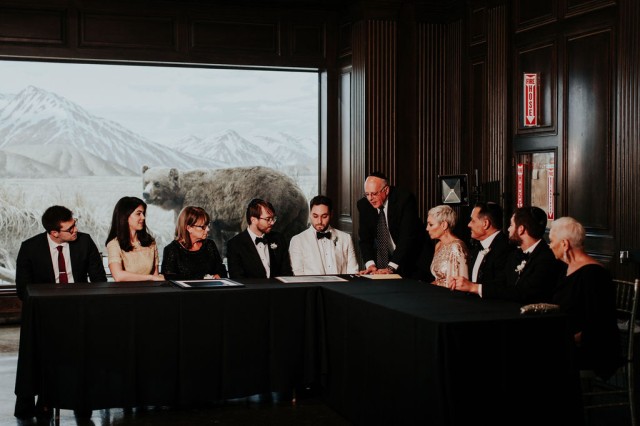 Derek Boeckelmann and Alex Kramer gather with their loved ones to sign their marriage license after the ceremony.