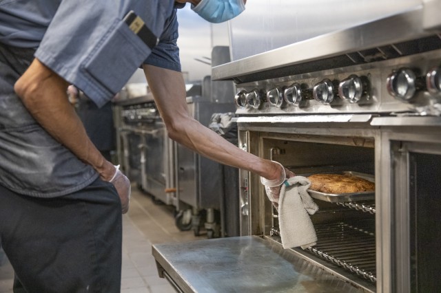 Man pulling loaf from oven 