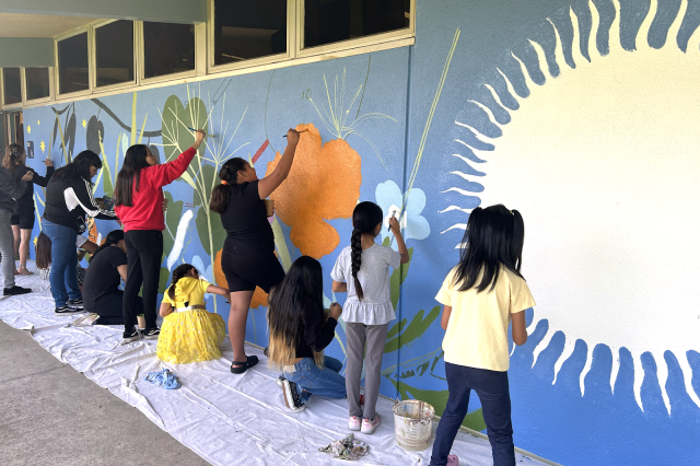 Students paint a mural designed by Studio Tutto