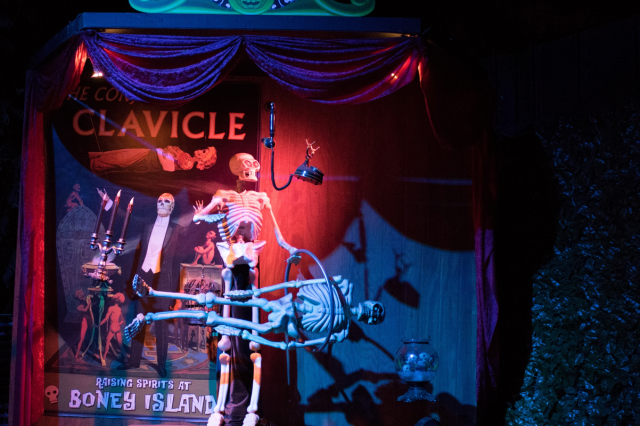 A stage with two replica skeletons, one holding a hood and the other suspended horizontally through the hoop