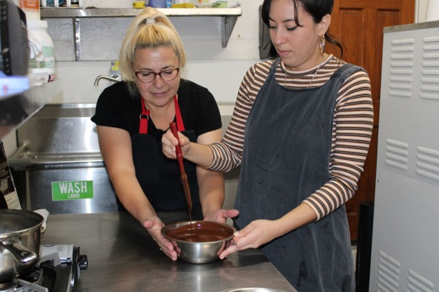 Two people standing at kitchen melting chocolate in a bowl