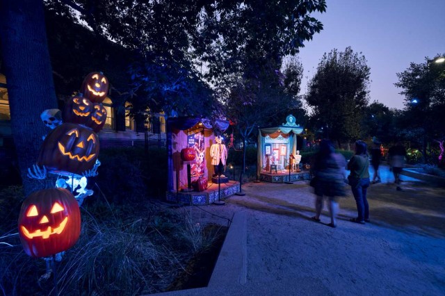 Visitors on a path with lit-up stacked pumpkin faces and stages