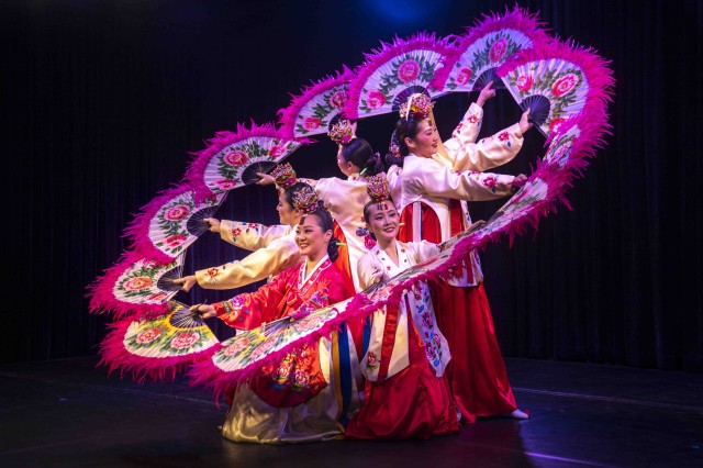 Dancers in wearing red and white holding fans to form one circular shape