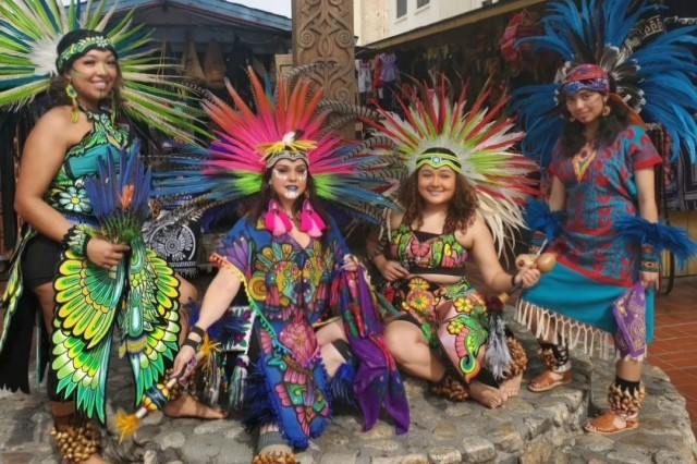 Dancers in multi-colored fringed outfits with feather headdresses