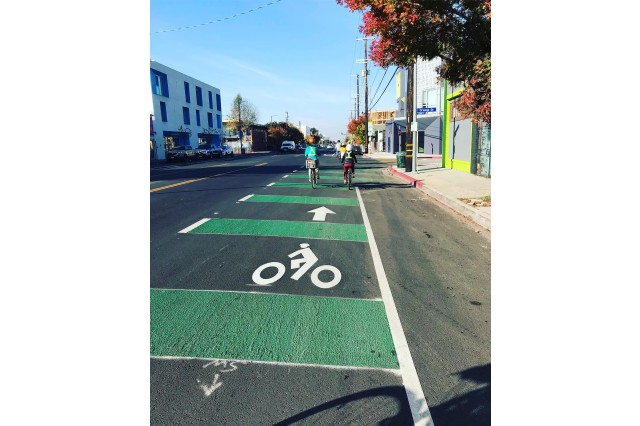 Looking down a white and green-striped bike path with two cyclists further down the street.