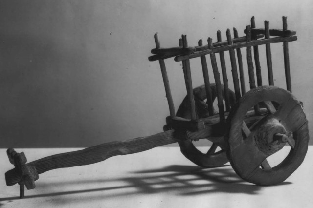 Antique photo of a small wooden wagon with the yoke resting on the ground and two thick rear wheels