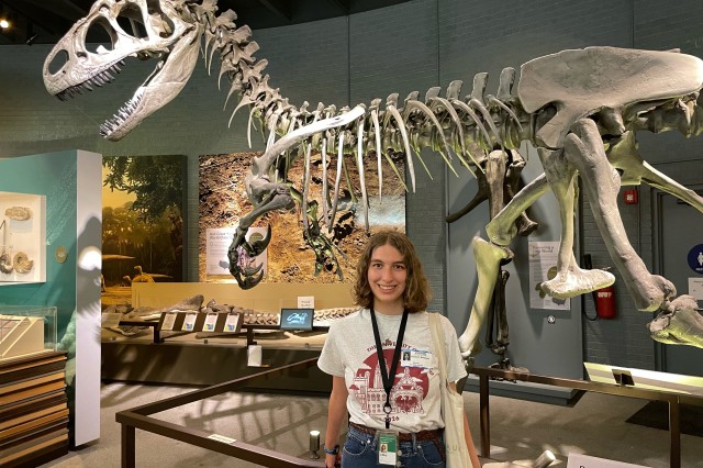 Libby Konjoyan standing in front of a dinosaur skeleton