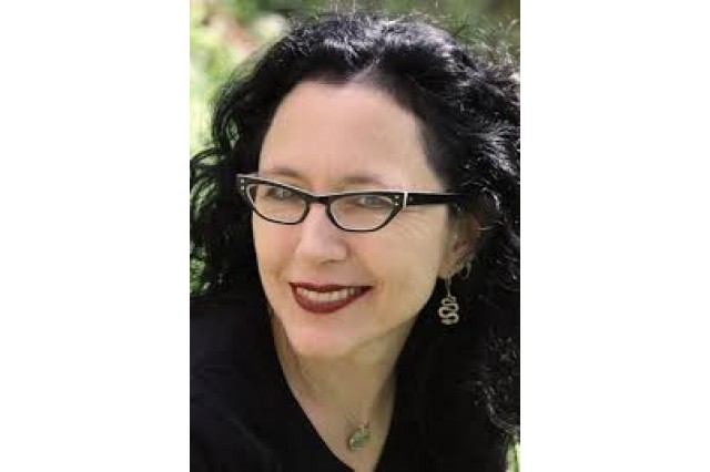 Corinna Bechko with black hair wearing cat-eye glasses and a black shirt