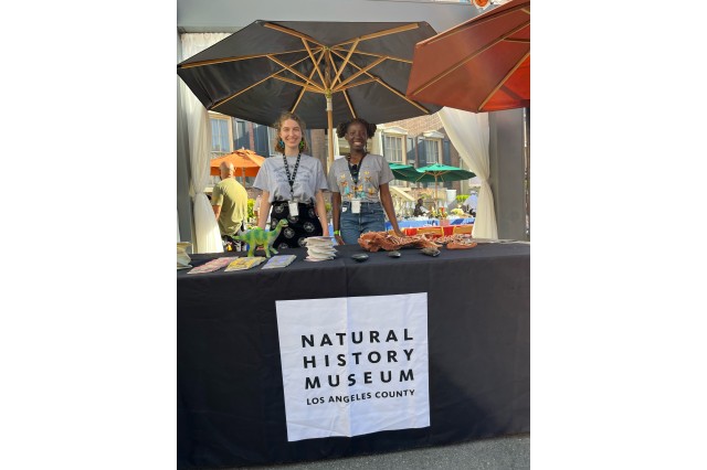 Libby Konjoyan and Ayomi Fadaka at a table with specimens and cards, underneath umbrellas