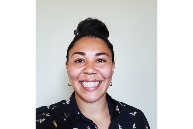 Head and shoulders portrait of Jazlyn Mooney, smiling and wearing a black shirt