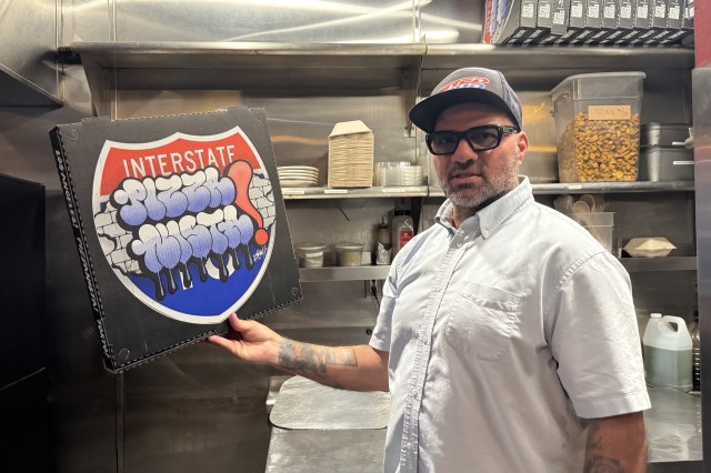 Man in a restaurant kitchen holding a custom designed pizza box for the brand Pizzanista!