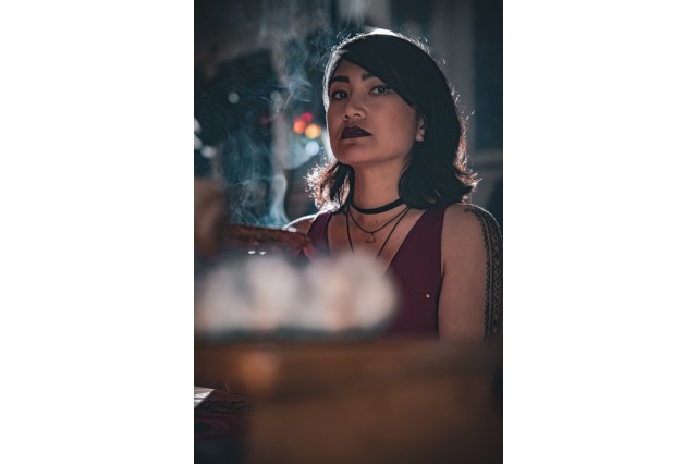 Head and shoulders portrait of Sapphire Sandalo with black hair flipped up at the shouulders and a red sleeveless top