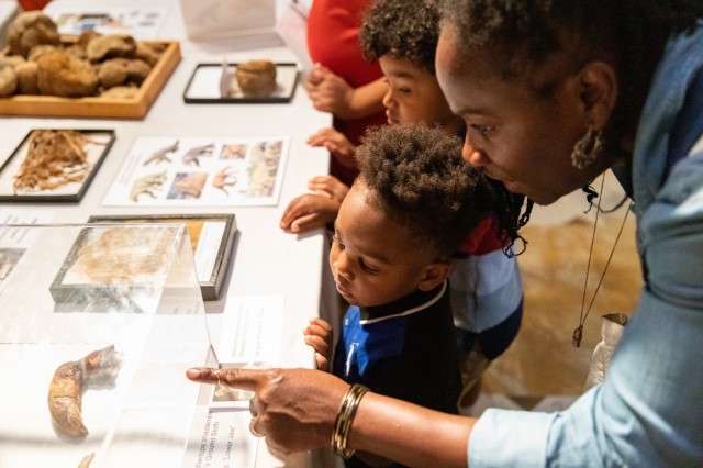Mother leaning over a child and pointing at specimens on a table