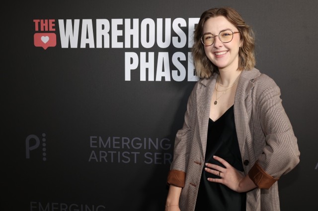 Austin Olivia Kendrick wearing glasses, a tan jacket, and black shirt against a gray background with Warehouse Phase in white capital letters