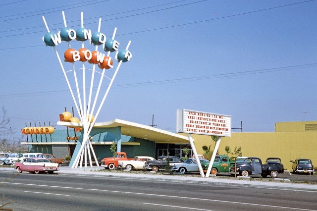 Wonder Bowl spelled out in white letters against blue and orange balls on white poles in the sky above a building on the side of the road