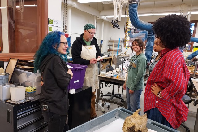 Interns meeting with fossil preparators with a specimen skull in the foreground