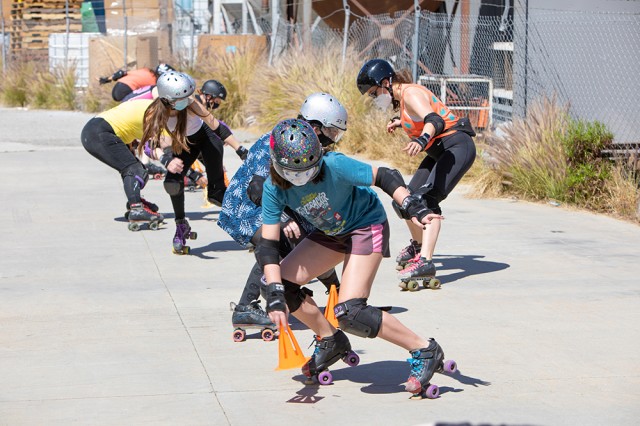 Skaters with helmets leaning over and doing skate drills