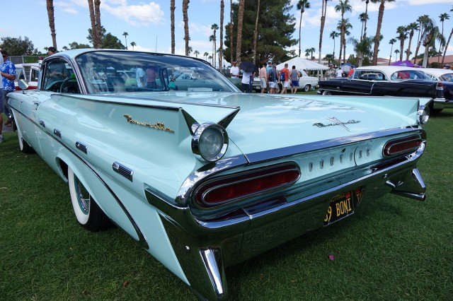 Robin egg&#039;s blue Bonneville car with spiky ridges in the hood, on a green lawn with palm trees in the background