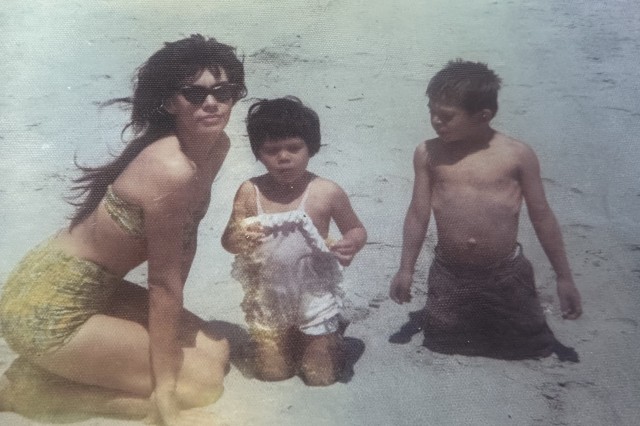 Young Sam Bearpaw is a young boy in shorts, alongside a womanand another small child in swimsuits