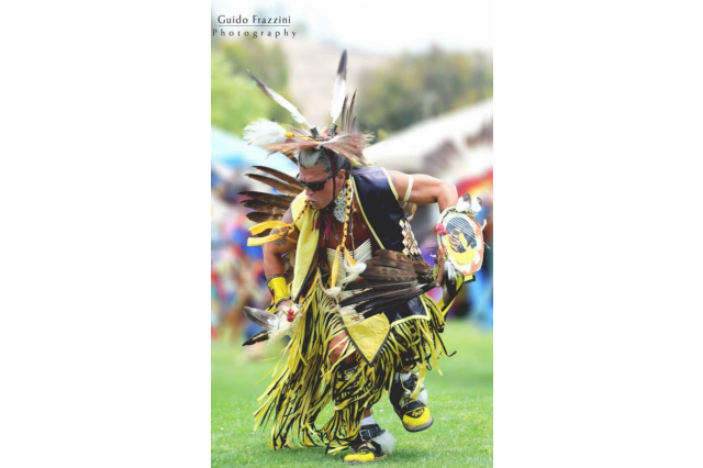 Sam Bearpaw dances in regalia at a powwow.
