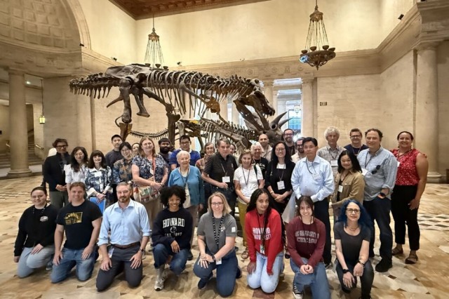 Group of alumni gathered in front of a dinosaur skeleton