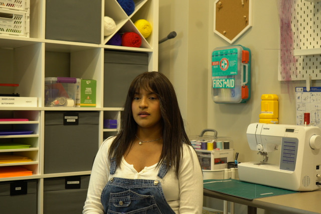 Woman sitting in front a sewing machine and cabinets