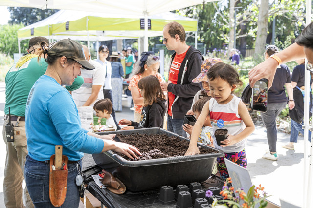 Child with hand in a tub of dirt on a table