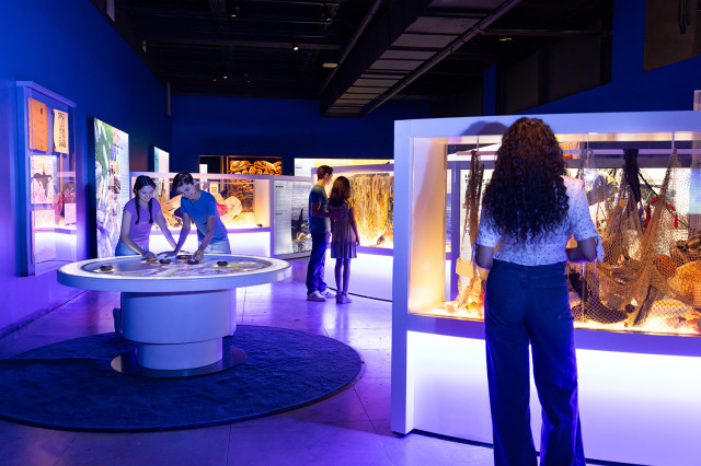 Visitors looking at displays in a darkly blue and purple lit room