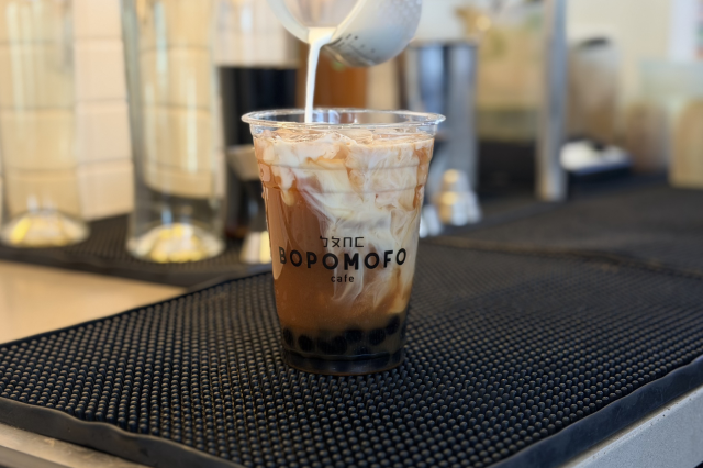 A tight shot detailing the stark white layer of lactose-free milk suspended perfectly between a colorful fruit juice base and a dark green matcha pour.