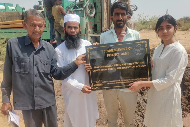 Four people holing up a plaque