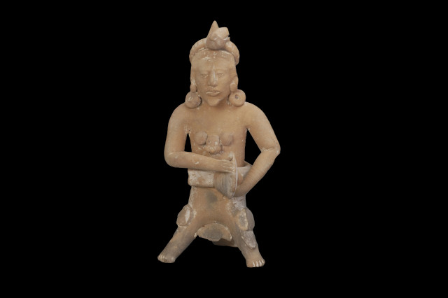 Ceramic figurine of a Mesoamerican ball player grasping its belt.