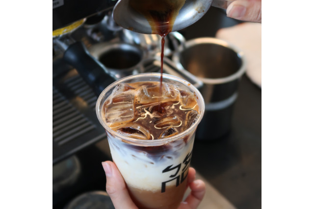 close of os drink with latter being poured over ice  -layered drink with brown and white