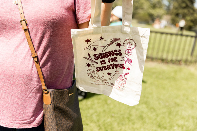 Closeup of a someone holding a reusable bag that says "Science Is For Everyone"