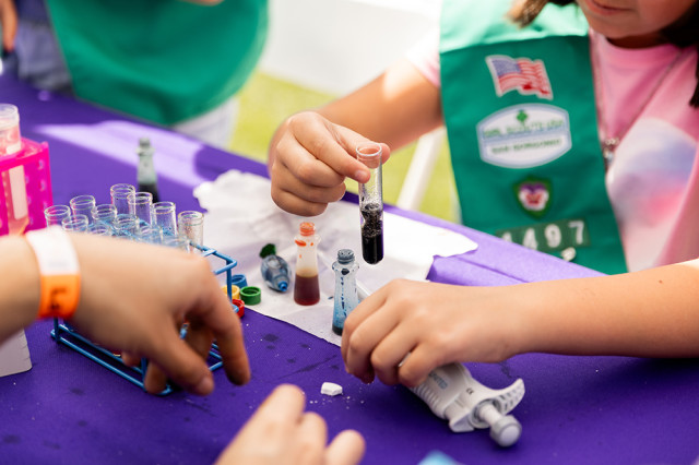 Close-up of a child's hands holding up a test tube with purple liquid