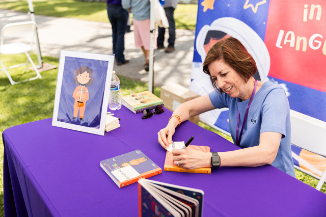 Woman at a table signing a book