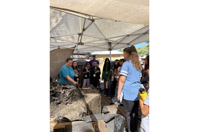 Students standing around Laura Tewksbury and a fossil mound