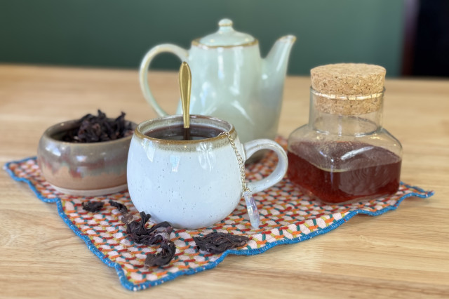 Hot cup of tea on a placemat next to the fresh ingredients used to make it.
