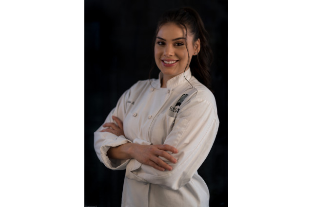 Young woman posing for a culinary school photo in her chef's apron.