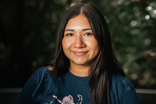 Head and shoulders portrait of Haidie Mendiola, against a leafy green background