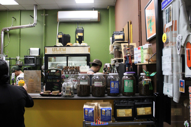 Coffee containers line the storefront counter of Ulew Coffee & Juice