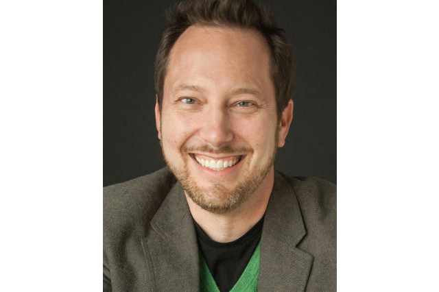 Head and shoulders portrait of Lee Supercinski smiling and looking at the camera
